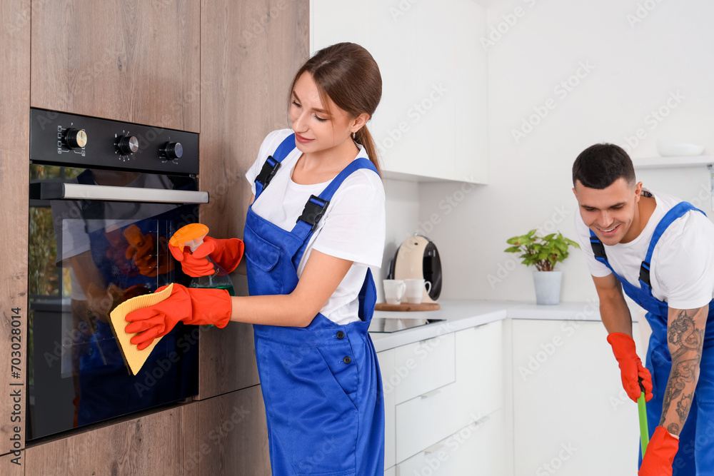 Wall mural female janitor cleaning built-in oven in kitchen