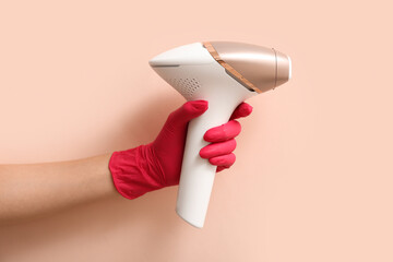 Female hand in rubber glove with modern photoepilator on color background, closeup