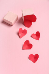 Composition with box and red paper hearts on pink background. Valentines Day celebration
