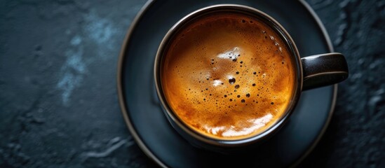 Top view of hot espresso with crema on a black background, focused