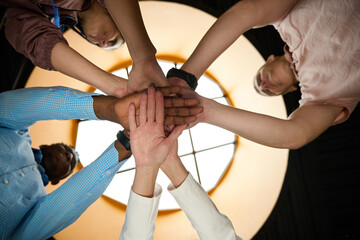 Fototapeta na wymiar Hardworking colleagues folding hands together as symbol of friendly team
