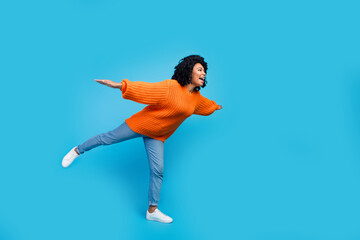 Fototapeta na wymiar Full length photo of lovely young lady flying spread hands plane bird wear trendy knitwear orange garment isolated on blue color background