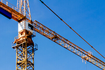 Construction crane tower on blue sky background. Crane and building working progress. Worker. Construction concept. New buildings with a crane. Tower crane