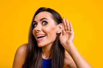 Photo of tricky excited woman wear blue top arm ear listening empty space isolated yellow color...