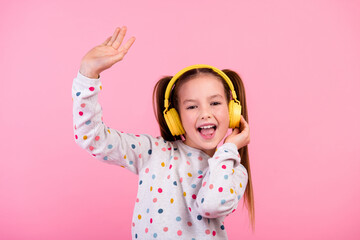 Photo of overjoyed small girl with tails wear stylish sweatshirt touch headphones raising arm up...