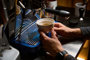 Barista pouring espresso using coffee machine for brewing hot beverage