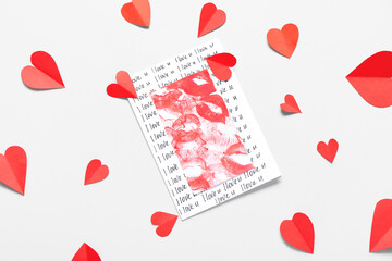 Composition with greeting card and red paper hearts on light background. Valentine's Day celebration