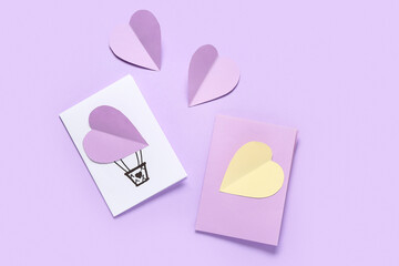 Beautiful greeting cards and paper hearts on lilac background. Valentine's Day celebration
