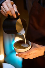 Fototapeta na wymiar Barista pouring froth milk in coffee making caffe latte art serve to customer