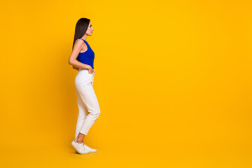 Fototapeta na wymiar Full length photo of positive good mood woman wear blue top looking empty space isolated yellow color background