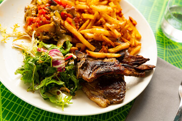 French dish, grilled lamb ribs served with french fries, fresh greens and stewed vegetables