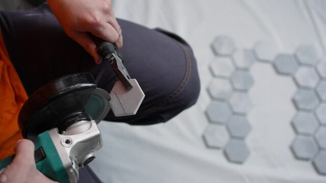 The master cuts the tiles. A tiler cuts tiles for laying on the floor. The master skillfully wields a tile grinding tool.