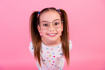Photo of adorable small girl with tails hairstyle wear stylish sweatshirt in glasses staring at you isolated on pink color background - obrazy, fototapety, plakaty