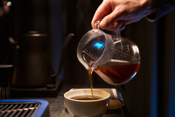 Fototapeta na wymiar Coffee maker pouring hot aromatic Americano into cup