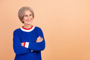 Portrait of positive senior lady wear blue jumper in eyewear arms crossed look at offer empty space...