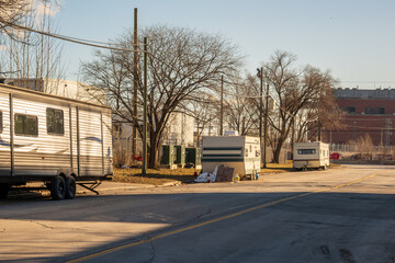 housing crisis: older travel trailers setup on a public street in an industrial section of a big...