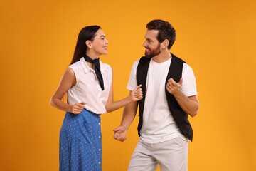 Happy couple dancing together on orange background