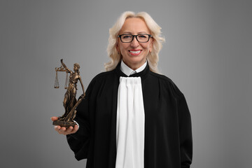 Smiling senior judge with figure of Lady Justice on grey background