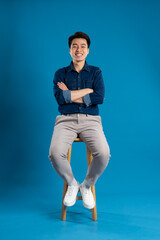 Portrait of young Asian business man posing on blue background