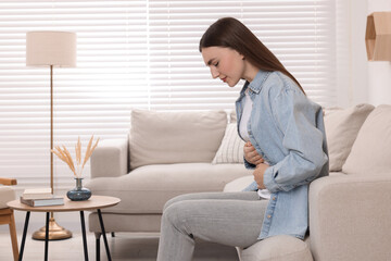 Fototapeta premium Young woman suffering from stomach pain at home