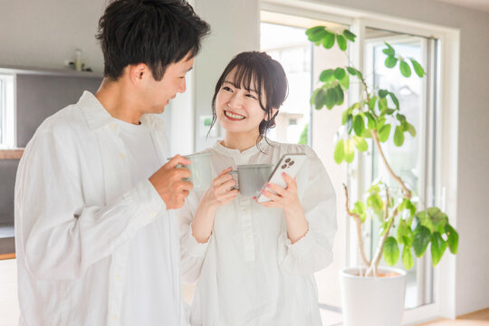 家のダイニングでコーヒーを飲みながらスマホを見る夫婦・カップル
