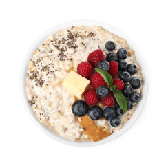 Tasty boiled oatmeal with berries, chia seeds and peanut butter in bowl isolated on white, top view
