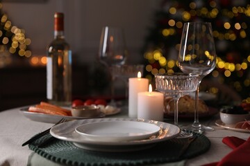Christmas table setting with burning candles, appetizers and dishware indoors