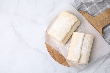 Raw puff pastry dough on white marble table, top view. Space for text