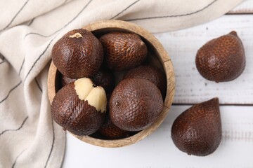 Fresh salak fruits in bowl on white wooden table, top view