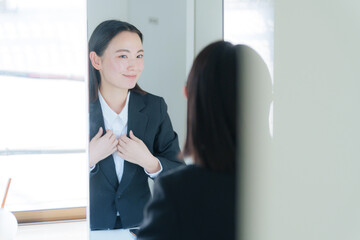 洗面所の鏡を見る若いビジネスウーマン（美容）