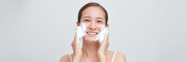 Satisfied girl with bare shoulders applying cleansing beauty product on cheeks. Banner