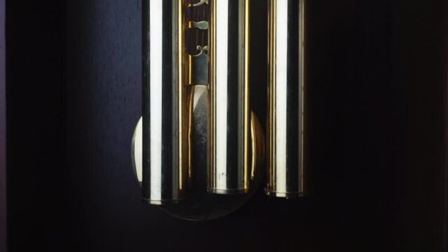 pendulum swinging back and forth, in a grand father clock, pendulum motion