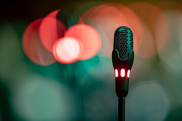 Macro photo of a black microphone with a blurred lights as background.