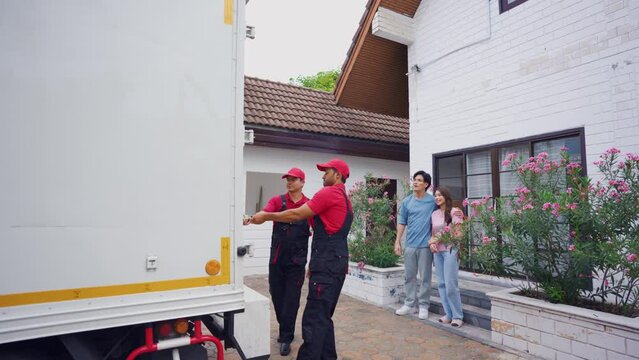 Asian young couple look at truck car while moving to new house together.