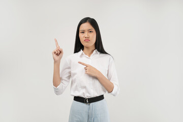 A young Asian woman wearing a white shirt points upward with one finger while crossing her arms as if indicating a bad idea or direction in a bright indoor setting