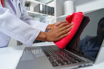 medical professional, likely a female doctor, sanitizing a desk with a red cloth and disinfectant...