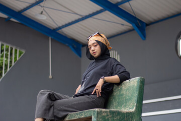 Asian female model in jeans and a black shirt, sitting on a tennis court with a bandana and glasses