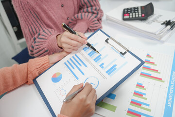 two individuals are engaged in accounting work. One person is wearing a pink sweater, and they both...