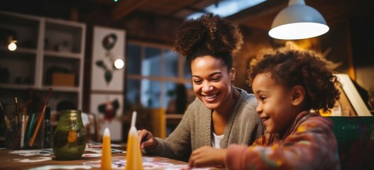 Happy African-American mother and daughter painting and crafting together in a well-lit art studio. - obrazy, fototapety, plakaty