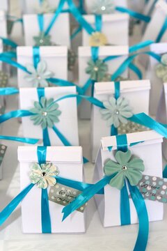 White gift boxes with blue ribbons  and flower emblem on a table