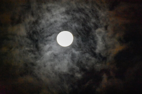 Night sky with full moon. Concept of spooky, horror, Halloween theme and mystery. Dramatic clouds in the moonlight from full moon. Dark gothic surreal background.
