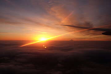 Fototapeta na wymiar sunset or sunrise above the cloud with top of a mountain taking from a flight - 1