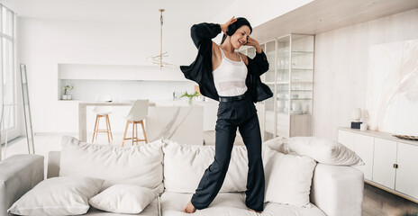 Joyful woman in business attire dancing at home, expressing freedom and happiness