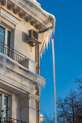 Vertical view of a residential city house covered with icicles and ice in winter