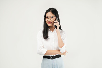 Fototapeta premium Photo of a young Asian woman smiling while talking on the phone, dressed a white shirt and isolated on a white background. 