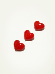 Three three-dimensional glossy red hearts lined up diagonally.