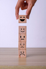 Hand putting wooden cube block with smiley icon. The best excellent business services rating...
