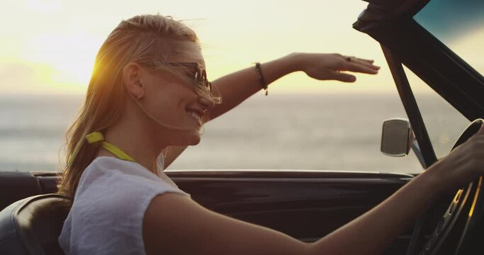 Woman on road trip with car, ocean and freedom in nature, sunset view and excited driver on holiday. Happy travel in convertible, fun on adventure and journey at beach with dance, smile and summer.