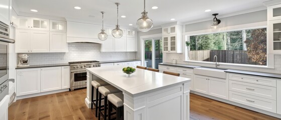beautiful white kitchen in new luxury home with island, pendant lights, hardwood floors, and stainless steel appliances
