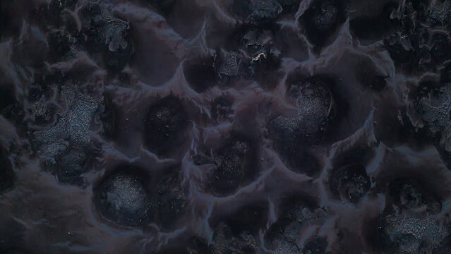 Drone top down view of black grey textured mound piles with low weaving pattern of water